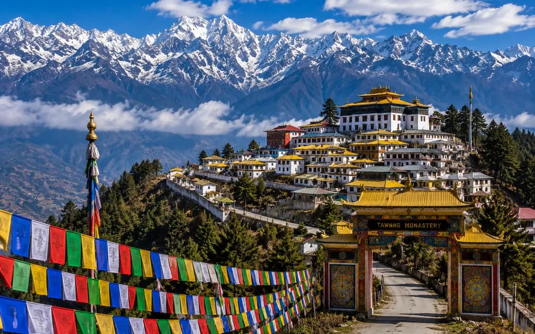 The Tawang monastery on its ridge, prayer flags and snow peaks behind